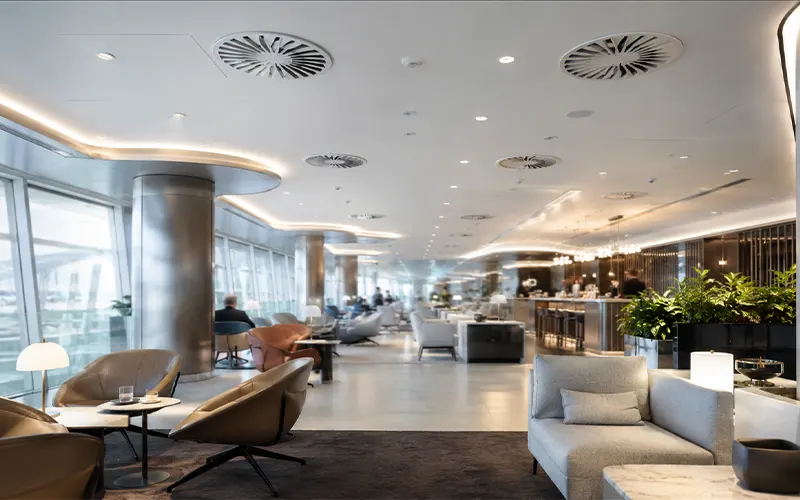 Sistema de filtración de aire en una sala lounge de aeropuerto con difusores HVAC en el techo.