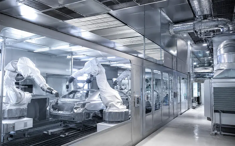 Instalación moderna de fabricación automotriz con robots de pintura y sistema de filtración para cabinas de pintura.