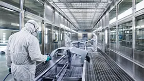 Operario con traje de protección en una cabina de pintura industrial para procesos de recubrimiento.
