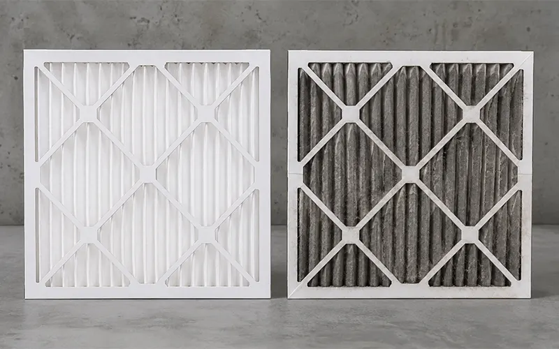 Comparación entre un filtro de panel HVAC plisado limpio y otro usado cargado de polvo.